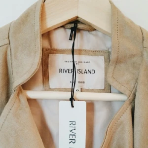  - Mocka jacka från River Island, sand färg med guld detaljer - Storlek 32, passar XS och S, aldrig använd med prislapp kvar (säljer pga fel storlek =( ) 