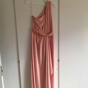  - En underbar långklänning från ASos, skulle använts på bröllop men blev förhinder. Så oanvänd. Den har öppen rygg, en-axel och snygg slits på benet. 