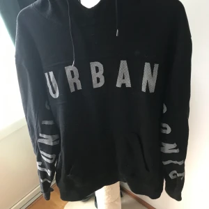 Hoodie  - Svart hoodie med tryck på bröst och armar, okej skick! Storlek XL men är mer som en L.