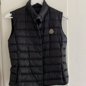 Moncler Väst - Säljer denna jättefina moncler väst. Västen är svart och är en av deras ”longue seison”. Använd men fortfarande i bra skick. Perfekta västen, då man på sommaren och våren kan ha den bara som den är. På vintern är den perfekt att ha under en kappa som ett extra lager. Om du vill dra på något till gymmet eller affären eller liknande. Säljes pga för liten storlek för mig. Kontakta mig för fler bilder eller information. Kan mötas upp och leverera men köparen står för leveransen. Originalpris ca 500€. (ÄKTA) Ps. Priset kan diskuteras då jag vill bli av med den och att den får användning istället för att den ligger och skräpar hemma hos mig! 