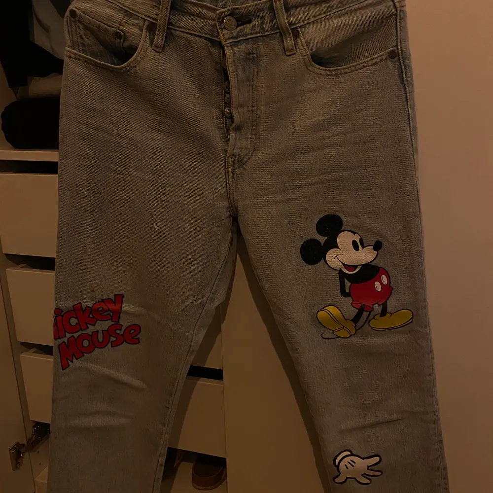 Ett par Levis x Mickey Mouse 501. Det är en fin ljus tvätt med coola tryck av Mickey Mouse. De är i storlek W28 L26, alltså en lite cropped modell. . Jeans & Byxor.