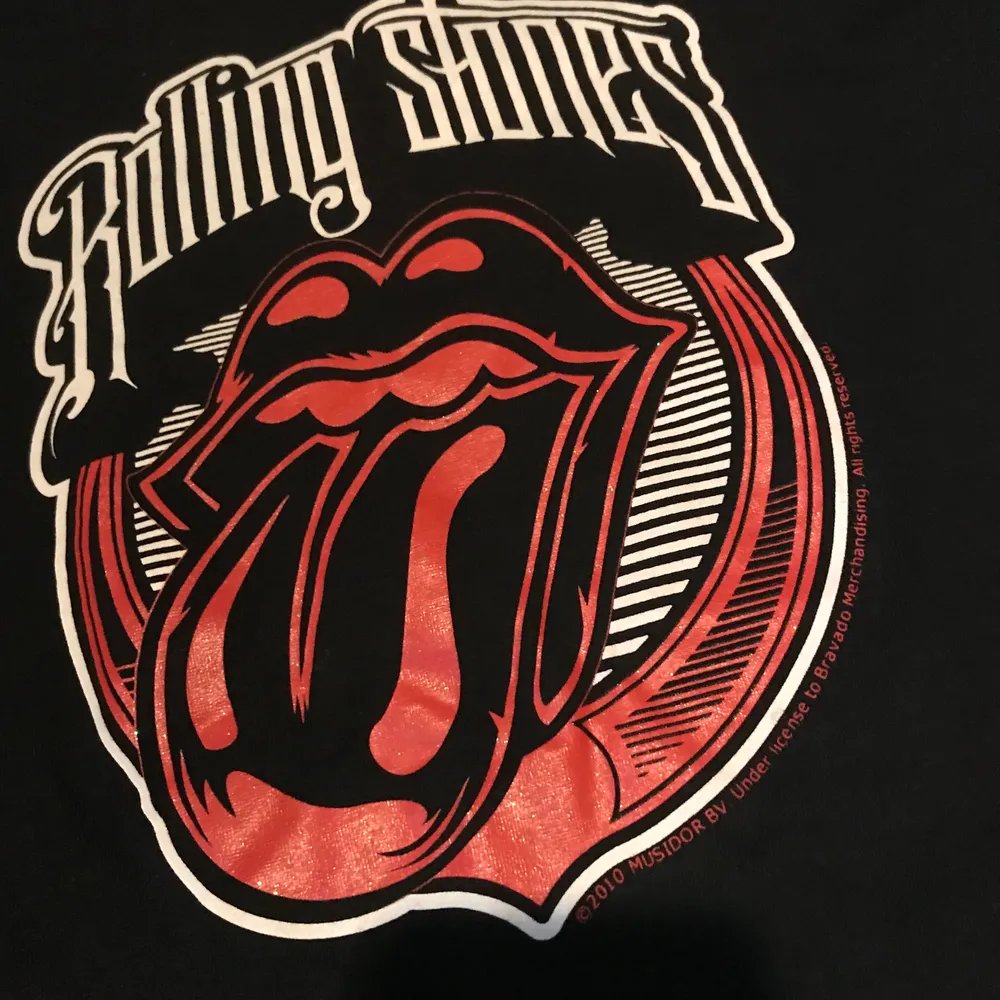 En svart band tröja med Rolling Stones motiv med glitter. Oanvänd. Skulle se bra ut om man cropped den men det låter jag köparen bestämma. Kan mötas upp i Stockholm eller posta. Frakt 44kr. T-shirts.