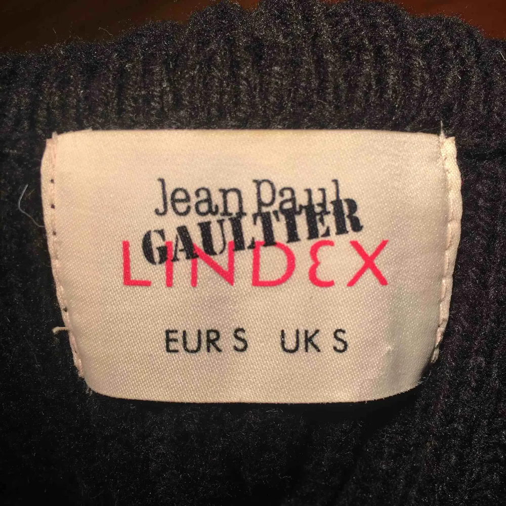 Svart stickad polotröja med blixtlås-detaljer, från Lindex X Jean Paul Gaultier kollektion. Tröjan är inte använd mer än en gång, så den är i princip i nyskick. Säljer då den inte kommer till användning för mig. Frakt ingår!. Stickat.