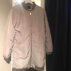 Bomberjacka  - En längre bomberjacka, säljer den för jag har aldrig använt den. En ljusgrå med guldiga detaljer. 