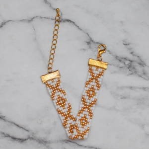 Armband  - Pärlat armband i vit och guld, passar de flesta handleder. Obs! De är inte orangea som på bilden, Photoshop ändrar färgerna för mig 🙃 11:- i frakt, fri frakt vid köp över 100:-.