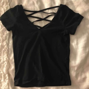  - Svart t-shirt med korsade band på ryggen🥰 bra kvalité och sparsamt använd🌟 frakt ingår i priset🤩