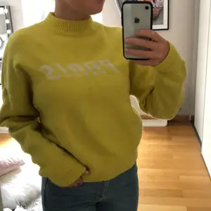 Super trendig gul stickad tröja med texten ”Paris” på, bra skick 
