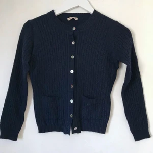  - Marinblå, ribbad kofta med knäppning och fickor. Supersöt! Förmodligen ull, lappen borta. Känns gedigen. Gott skick! Luddig då den legat med annat ylle & fotats med blixt för att visa strukturen. Fixas förstås vid sälj!