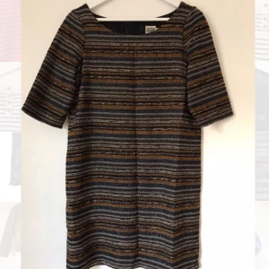  - Snygg klänning från Twist & Tango med inslag av tunna silvertrådar och dragkedja i rygg. Fint skick! Storlek 38