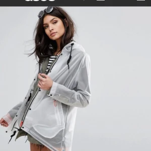  - Stilren regnkappa i modern design tillverkad i 100% polyuretan vattentät med dragsko i midjan och två snedställda framfickor. Oanvänd med lapp kvar originalpris 1999 kr i butik