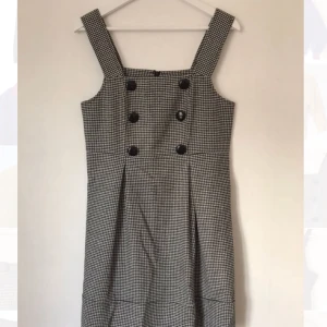  - Snygg klänning med hängslen och hundtandsmönster i tunt ylle och sidenfoder och pressveck. Osäker på storlek men skulle gissa på 36-38. United Colors of Benetton