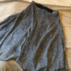  - Elegant klassisk kjol som går över knäna. Lätt och luftigt tyg i snygga blå nyanser. Blixtlås i sidan. Storlek S, men passar även M.