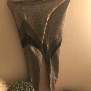  - Ett par oanvända gråa träningsbyxor med mesh på låren. 