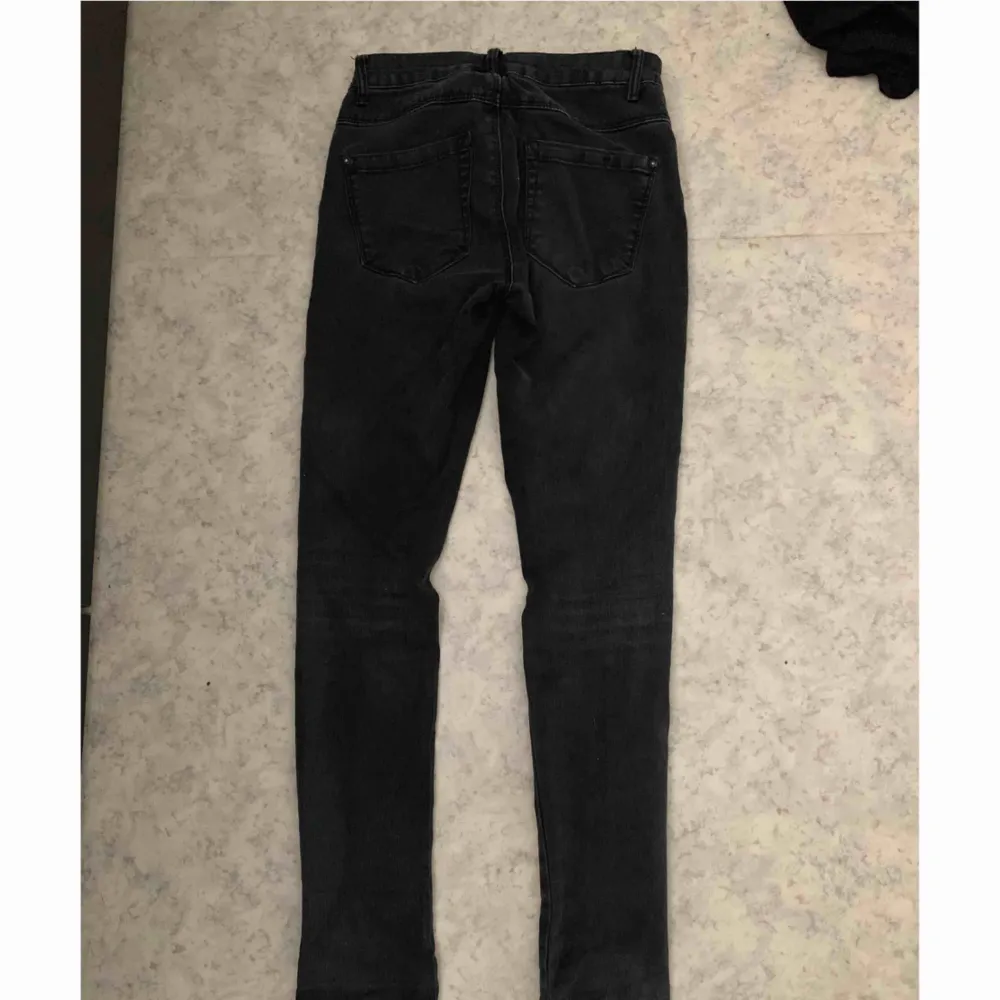 Ett par mörkgråa jeans med hål i knäna,   köpta ifrån Nelly.  Storlek XS. Jeans & Byxor.
