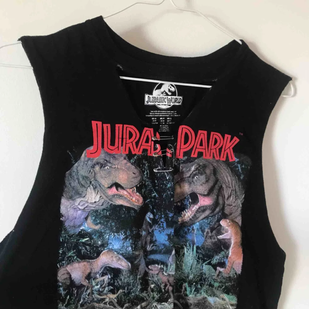 🦖 Jurassic World tank top från forever 21. Har en utklippt v neck med en ”chocker” som lätt går att klippa bort om man skulle vilja. Den är ganska lång men går att klippa. Säljer för 40 kronor + frakt! . T-shirts.