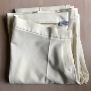 Låga vita kostymbyxor - Låga gräddvita kostymbyxor med utsvängda byxben. Från ett märke som heter italia N.I.C.E. St L men liten i storleken. 