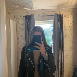 Skinnjacka med nitar - Snygg skinnjacka med nitar på kragen och dragkedja i slutet på ärmen. 