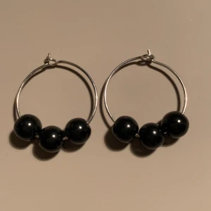 Örhängen - Ett par ringar med svarta vaxpärlor. Paret kostar 50 kronor och 11 kronor i frakt. 