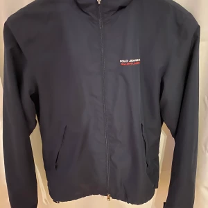 Jacka Tommy hilfiger - En blå vindjacka från Tommy hilfiger i storlek s. Enda som är förstört är den där grejen på dragkedjan (andra bilden). Annars inget annat. Sitter jättesnyggt på!