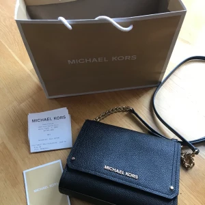 Michael Kors väska - Liten axelremsväska i skinn som även kan användas som clutch. Inköpt i USA på Michael Kors butik, kvitto finns. I jättebra skick, som ny!