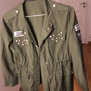 Jacka storlek S- M - Militärgrön jacka med jättefina pärlor och tryck på. Helt oanvänd.🍃 Jackan får även en ny passform när ärmarna vicks upp en aning 💫 (Skriv för fler bilder, kunden står för frakten som summan varierar beroende på plaggens vikt) 