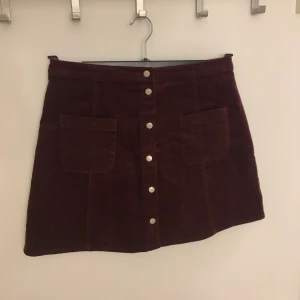 Kjol i manchester stl S - 🌸Lila kjol i manchester i stl S från Ginatricot. Knappar hela vägen framtill. Knappt använd, fint skick! Kan skickas, köparen står för frakten.🌸