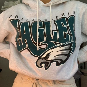 Hoodie med tryck - Jag säljer denna väldigt snygga gråa Hoodie med texten Eagles. Den sitter  jättefint och är väldigt skön. Jag har köpt den secondhand för inte så länge sedan. Jag har aldrig använt den och det är i väldigt fint skick. Köptes för 400 säljs för 350! 