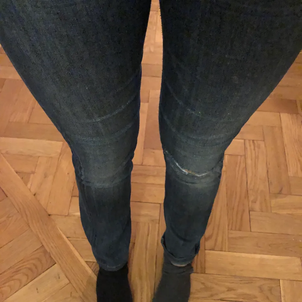 Mörkblåa jeans med ett hål på ena knäet och med en liten bootcut. . Jeans & Byxor.