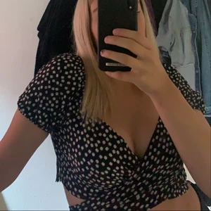 Topp - Svart topp med vita blommor. Storlek M sitter som en S. Kan knyta hur man vill. På bilderna ser ni 2exempel 💜 ( frakten betalar ni själva )  