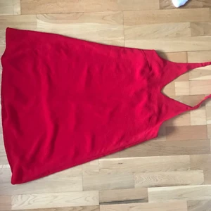 Rödklänning - Rymlig röd klänning som man knyter i nacken. Jättefint material och använd en gång.