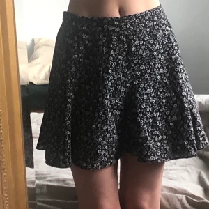 Blommig kjol - Svartvit kjol i småblommigt mönster. Använd ytterst få gånger så i fint skick! Storlek 34/XS (Frakt tillkommer)
