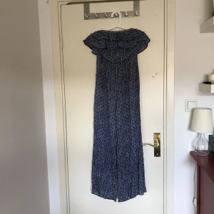  - En helt oanvänd byxdress i fint skick. Den har volanger upp till och stängs med en knapp baktill. Överdelen har resår som för att den sitter uppe.  Säljer den då den aldrig använts och tar upp plats i garderoben.   Frakt ingår inte i priset.