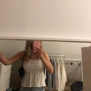 Vit topp - Vit bandou topp med volanger från Hollister. Den är i storlek XS men passar även S skulle jag säga då den är stretchig. Köpare står för frakt!