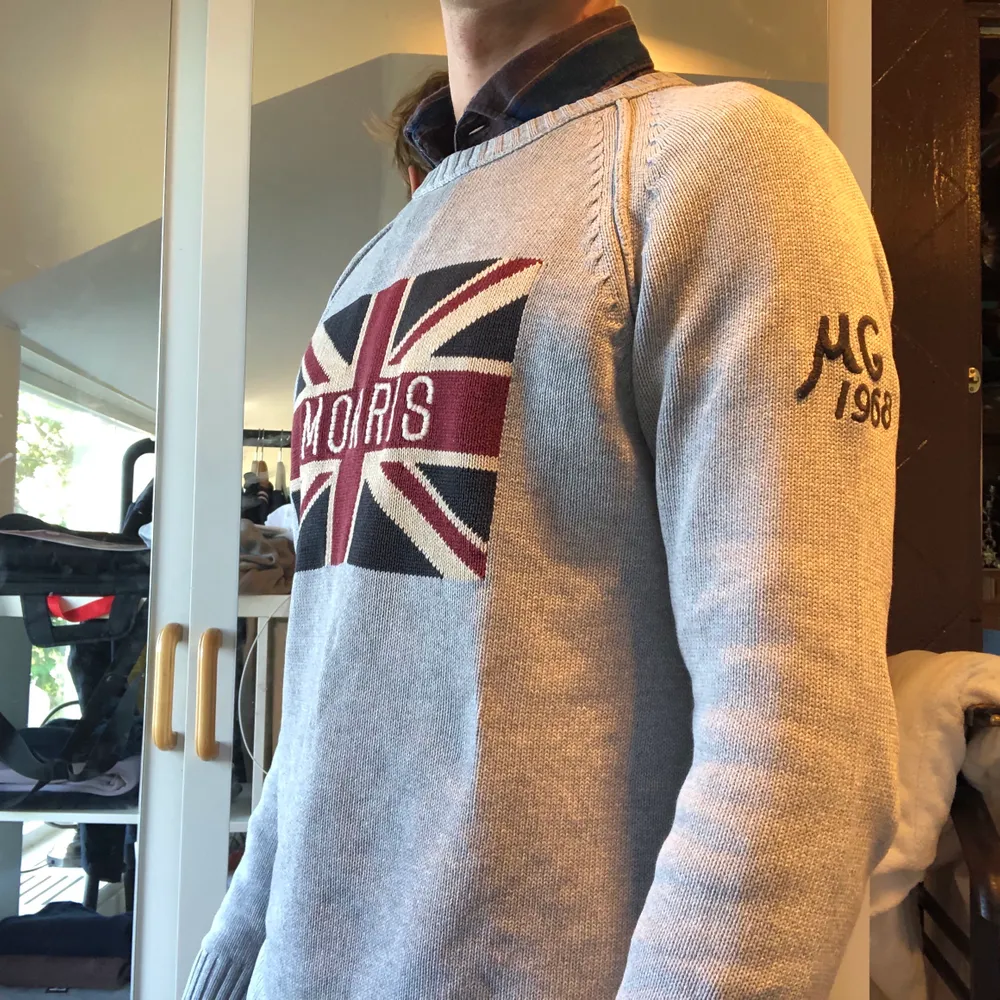 Klassisk Morris pullover med brittisk flaggmotiv. Den är i superfint skick generellt, små hål i armhålorna (som det oftast blir med stickade). Stickat.