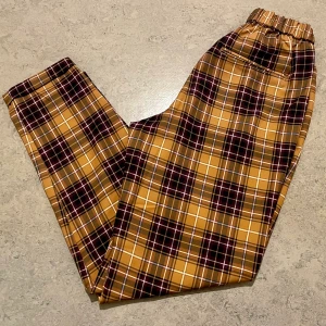 Rutiga byxor från Pull & Bear - Gul/lila/vit rutiga byxor med resår i midjan från Pull & Bear i storlek S. Säljer pga för små, passar nog XS bättre än S beroende på hur breda höfter man har💞 Frakt tillkommer!