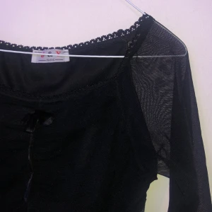 svart blus - svart blus med rysch och rosett där framme, med snygga ärmar. köpt på humana och väl älskad av mig, men i bra skick. den är lite tjockare tygg över kroppen, men med mesh över armarna. frakt ingår i priset! står ingen storlek men skulle uppskatta till M