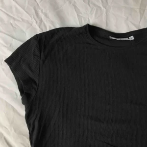  - Svart ribbad t-shirt från Weekday. Knappt använd och jättebra skick. Swish och frakten ingår inte! 