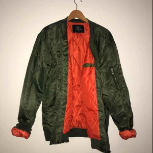  - maringrön bomberjacka med orange insida, storlek XL. Oanvänd. Frakt tillkommer!
