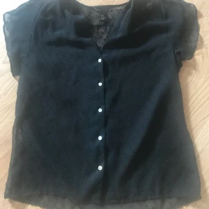 2 tröjor ifrån hm - 1: ett svart genomskillning kortärmad med svara prickar och lite v ringat. Den genomskillniga kortärmade är i storlek 34 och linnet i 38.