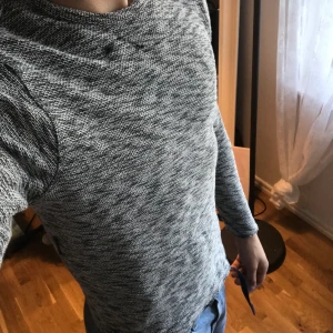 Grå tunn tjocktröja - Stickad tröja har en liten skada upp mot halsen 
