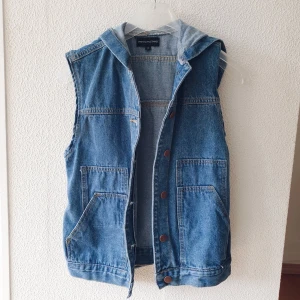 Jeansväst med luva i strl XS - En oanvänd väst i jeans i storlek XS. Snygg och clean i nyskick. Frakt tillkommer (+44kr). Samfraktar självklart om du köper mer! 