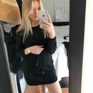  - Klänning med snörning i midjan och fickor. 