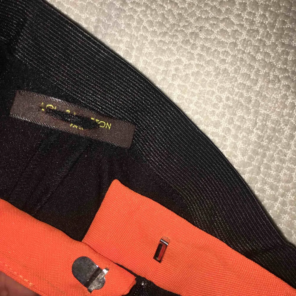 Svarta kostym byxor från Louis Vuitton som har en orange design på framsidan och är ett elastisk band runt höfterna (mid waist). Står inte storleken på byxorna men skulle nog säga det passar XS-S bäst. Priset går att diskuteras :). Jeans & Byxor.
