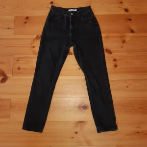 svarta NA-KD jeans storlek 34 - Svarta/svartgråa högmidjade mom-jeans från NA-KD. De sitter superfint men säljer dem då jag har växt ur dem. De är i jeansmaterial, det vill säga inte stretchigt material. Vi kan antingen mötas upp i hbg eller fraktar jag dem. 