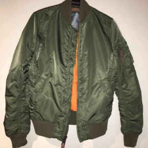  - Grön bomberjacka med orange insida från Alpha industries. Fint skick, knappt använd. Storlek xs  Nypris 1399, säljs för 500 kr