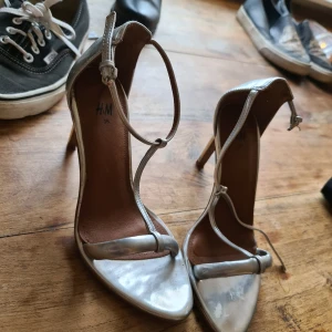 Silvriga klackar 🥰 - Hej, silvriga klackar från h&m. Fina! Lite missfärgning där foten sitter men ok skick 😊