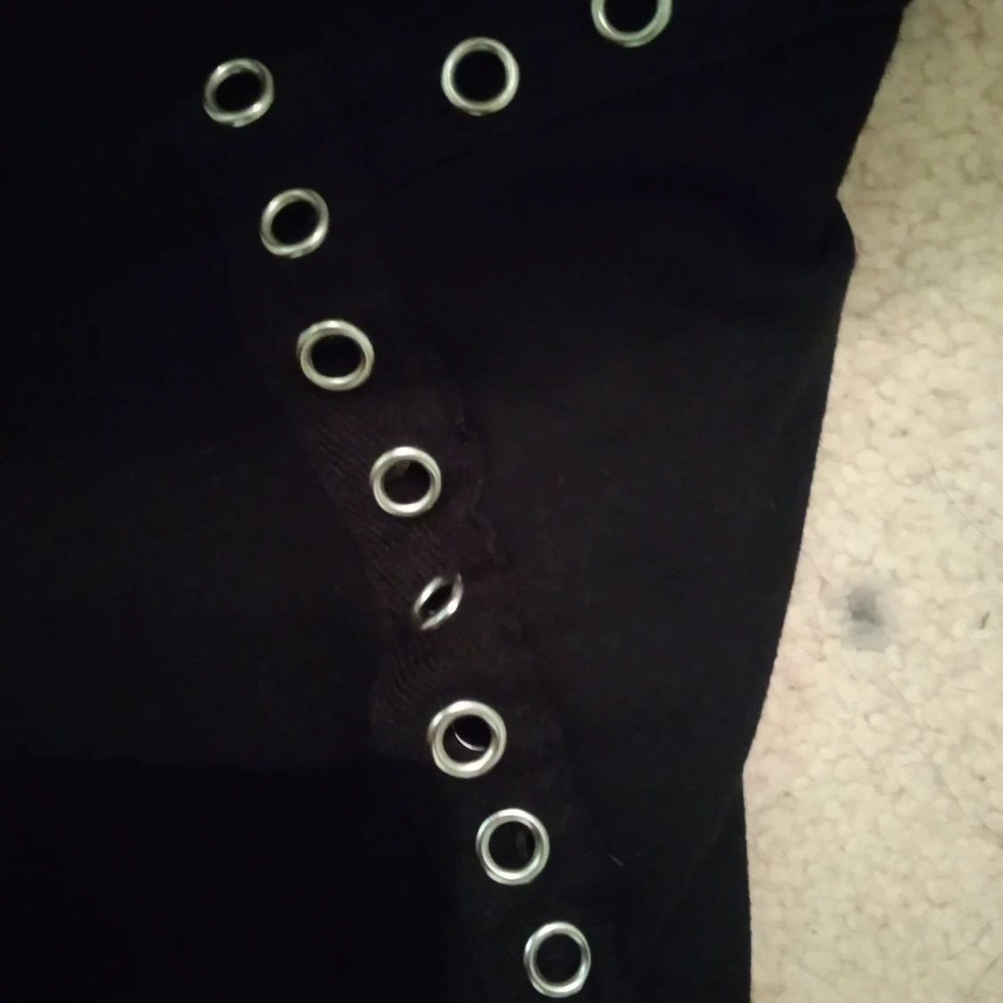 Svart tröja med hål i arméerna som syns 