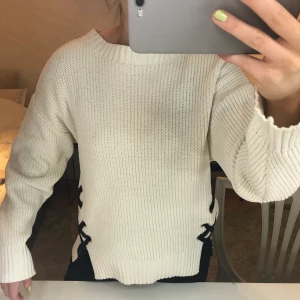 Stickad tröja - En krämvit stickad tröja med svarta knytningar på sidorna från Zara. Fin och i bra skick. Köparen står för frakten!