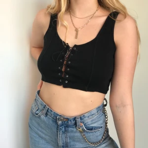 Svart croptop - Svart croptop som är snörad i mitten. Fint skick. Köparen står för frakt. Står M i tröjan men passar även S