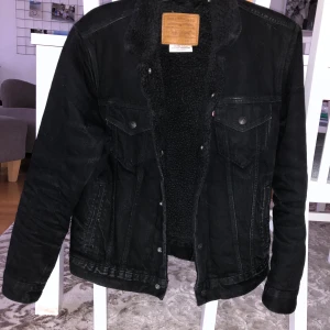 Äkta Levisjacka, varm och skön. Svart. strl:S - Sitter bra. Jeansjacka som funkar på vintern/våren/hösten. Ull/bomull inuti. Använd ett fåtal gånger och är i nyskick. Nypris:1600kr köpare står för frakt. Passar även om man har M.